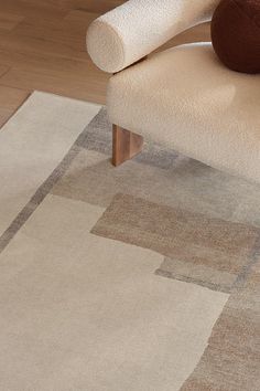 an area rug is placed on the floor next to a chair with a brown and white pillow