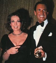 a man in a tuxedo standing next to a woman holding an award