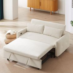 a white couch sitting on top of a hard wood floor next to a wooden dresser