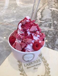 a cup filled with ice cream and raspberries on top of a marble table