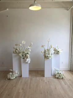 three white vases with flowers in them sitting on the floor next to each other