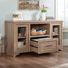 a wooden cabinet with drawers and books on it in front of a painting hanging on the wall