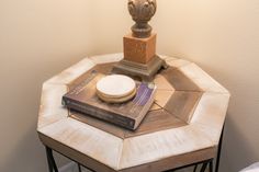 a table with a lamp and some books on it next to a small statue in the corner