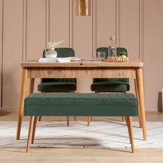 a wooden table with two green chairs and a small bench in front of the table