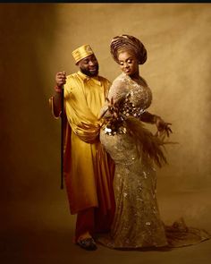 a man and woman dressed in african clothing posing for a photo with an umbrella over their heads