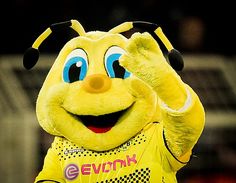 the mascot is waving to the crowd while wearing his yellow shirt and black headband