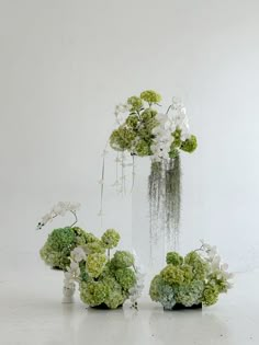 three vases filled with white and green flowers