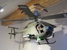 a helicopter hanging from the ceiling with two people in it's cockpit and one person inside