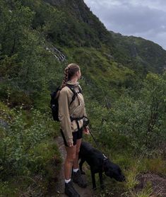 a woman and her dog on a trail in the mountains