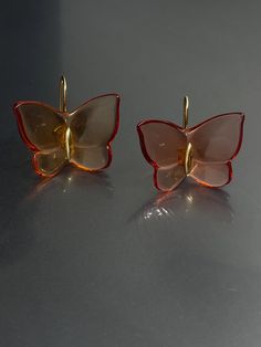 Elevate your style with these stunning Baccarat earrings. Crafted with yellow gold and amber tone crystal/glass, these earrings feature a beautiful butterfly design with a hook closure for easy wear. The dangle/drop style adds a touch of elegance to any outfit and the 1" length is perfect for the lobe area. These earrings are signed by Baccarat and boast a unique combination of beauty, nature, art, animals & insects, bohemian, and fashion & costumes themes. The crystal/glass material adds a spar Luxury Amber Drop Earrings, Luxury Yellow Gold Butterfly Earrings, Luxury Gold Butterfly Earrings, Gold Earrings With Butterfly Charm For Formal Events, Gold Earrings With Butterfly Charm For Formal Occasion, Gold Butterfly Earrings For Formal Occasions, Orange Pierced Earrings For Formal Occasions, Luxury Clear Earrings For Formal Events, Formal Orange Pierced Earrings