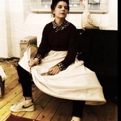 a woman sitting on top of a wooden floor next to a white bird in an air conditioner