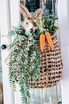 a basket filled with carrots and greenery on top of a counter next to a door