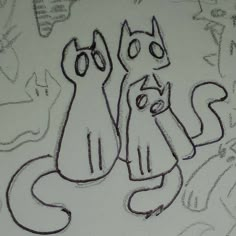 two cats sitting next to each other on top of a white paper with writing all over it