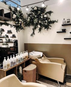 a hair salon with lots of white flowers hanging from the ceiling and chairs in front of it