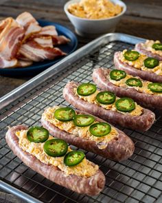 hot dogs with jalapenos and cheese on a cooling rack next to bowls of macaroni and cheese