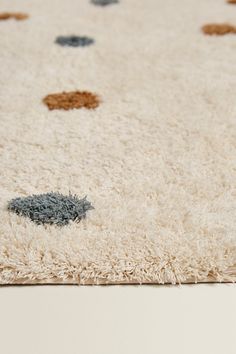 a white rug with black and brown circles on the top is shown in close up