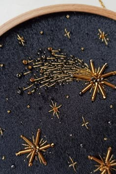 an embroidered wall hanging with gold stars and sparkles on it's black fabric