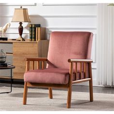 a pink chair sitting in front of a table with a lamp on top of it