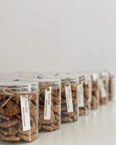 several glass jars filled with cookies on top of a white table next to each other