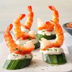 three shrimp appetizers on cucumber slices with dipping sauce in the background