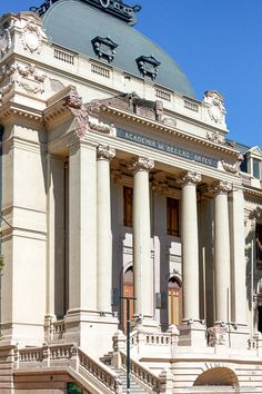 an old building with columns and pillars on top, in front of a blue sky