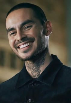 a man with tattoos smiling at the camera