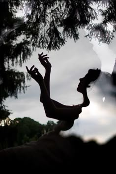 a woman standing in front of a tree with her hands up