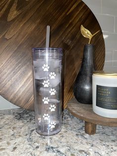 a glass with some paw prints on it next to a candle and a wooden tray