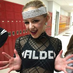 a woman in a black and silver outfit with her hands out to the side while standing next to lockers