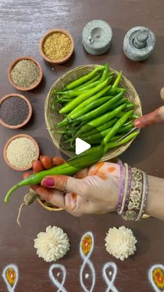 a person holding green beans in front of several bowls and spoons on a table