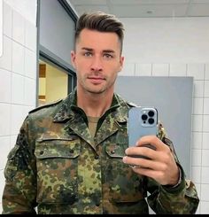 a man in uniform taking a selfie with his cell phone while standing in front of a mirror