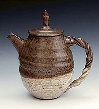 a brown and white tea pot with a handle on the top is sitting in front of a gray background