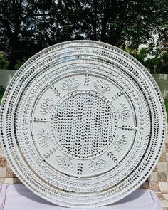 a large white plate sitting on top of a tile floor next to a garden wall