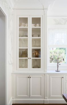 a white china cabinet with glass doors and shelves