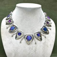 Here's a striking new necklace of handmade dichroic glass cabochons. They are set into fine silver bezels on domed, sterling, triangular drops. The domed drops are suspended on twisted and hammered wire links with silver granulation. A stunning accessory for special occasions. The video shows how some of the dichroic glass cabochons shift color as they move through different lighting, from blue and purple to pink and orange. It is light weight and comfortable to wear. The necklace is 19.75 inche Silver Glass Cabochon Necklaces, Silver Glass Cabochon Necklace, Silver Necklace With Cabochon Glass, Silver Fusion Necklace With Cabochon, Fusion Style Silver Teardrop Necklace, Silver Teardrop Necklace In Fusion Style, Silver Teardrop Fusion Necklace, Silver Drop Necklace With Cabochon, Silver Teardrop Necklaces With Unique Variations