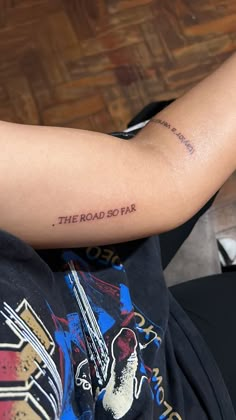 a person with a tattoo on their arm that reads the road 50 far and has a guitar in it