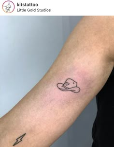 a person with a small tattoo on their arm that has a hat and lightning bolt