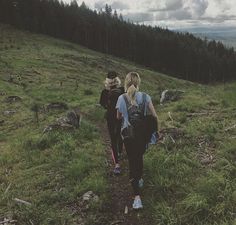 two people walking up a hill with backpacks