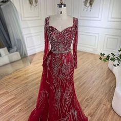 a red evening gown with long sleeves and beadings on the neckline, sitting on a mannequin