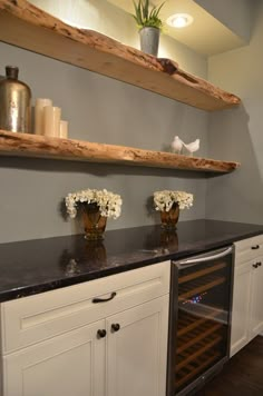 a kitchen with white cabinets and black counter tops, two wine racks on the wall