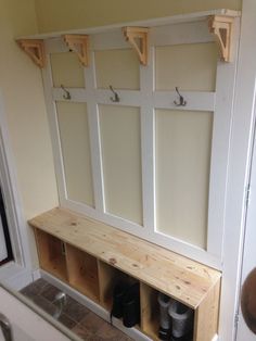 a wooden bench with several pairs of shoes on it in front of a wall mounted coat rack