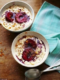 two bowls filled with food sitting on top of a wooden table next to spoons