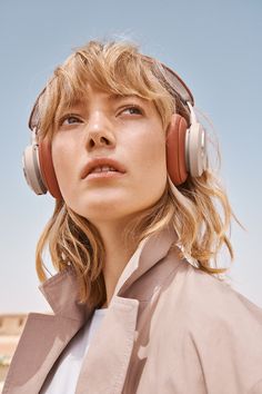 a woman with headphones on looking off to the side in front of a blue sky