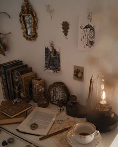 a table topped with lots of books next to a cup of coffee and a lamp