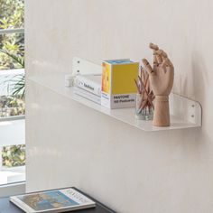 a shelf that has some books on it and a hand holding something up in the air