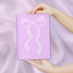 a hand holding a pink box with a white ribbon on it and the word grace written in cursive writing