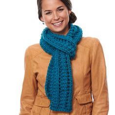 a woman wearing a blue knitted scarf and brown leather jacket smiling at the camera