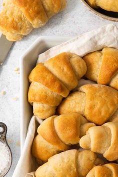 freshly baked bread rolls in a baking dish next to a bowl of salt and spoons