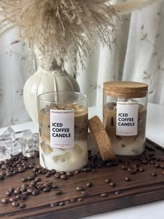 two jars filled with iced coffee and marshmallows sitting on a wooden tray