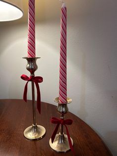 two candles with red bows on them are sitting on a table next to each other